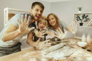 Hobby dla dzieci i rodziców Cute-little-girl-her-beautiful-parents-preparing-dough-cake-kitchen-home