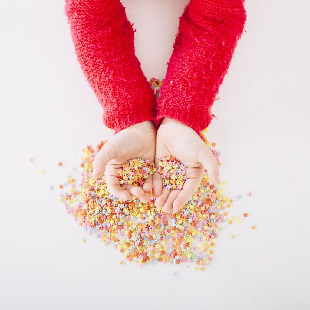 Pudełko sensoryczne dla dzieci DIY "Zrób to sam" Elevated-view-girl-s-hand-with-sprinkles
