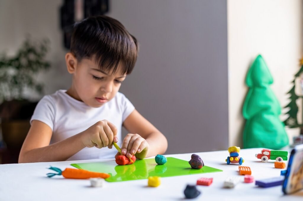 Rozwój zdolności motorycznych u dzieci: gry rozwijające zdolności motoryczne rąk Small-caucasian-boy-playing-with-colored-plasticine-making-figures-white-table-happy-child-idea