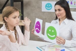 Inteligencja emocjonalna u dzieci i sposoby jego rozwoju Smiling-psychologist-showing-happy-sad-emotion-faces-cards-girl-child
